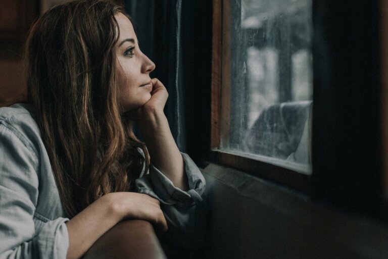 Mujer joven mirando por la ventana con expresión pensativa, imagen que ilustra la experiencia emocional del Trastorno Límite de la Personalidad