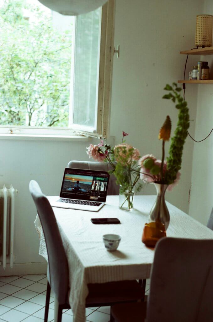 Laptop abierta sobre una mesa junto a una ventana, en un espacio doméstico tranquilo para una sesión de terapia en línea