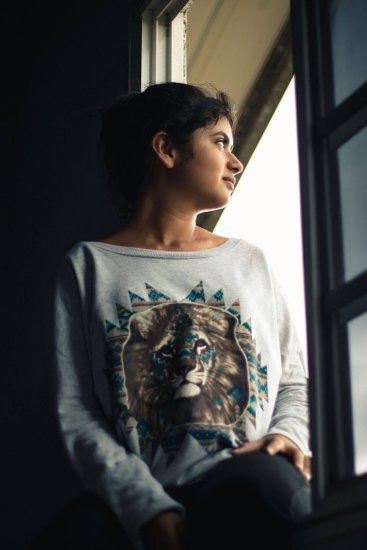 Mujer mirando pensativa a través de una ventana con luz cálida, imagen que evoca el momento de comprensión interior propio del insight psicológico
